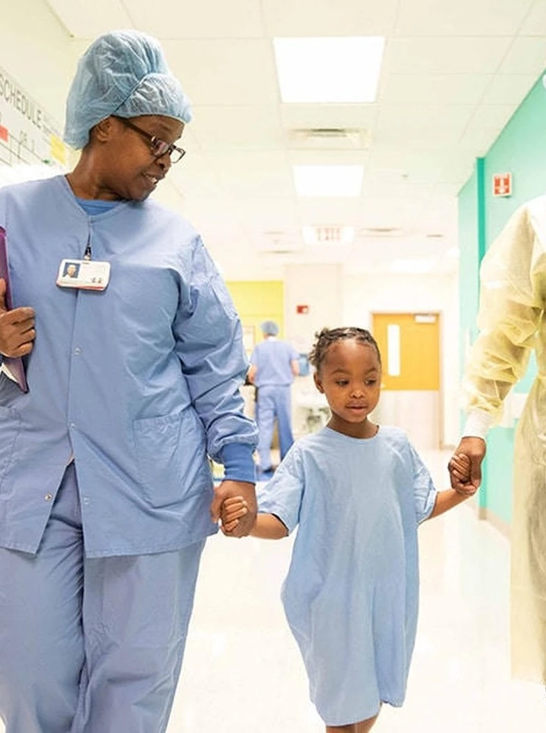 Illustrative image of a healthcare worker walking with a child.